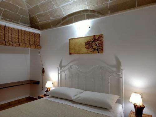 een slaapkamer met een wit bed en 2 lampen bij Case Vacanze Mariposa in Favignana