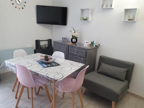 uma sala de jantar com uma mesa e cadeiras e uma televisão em apt cosy, 4 pers, plein centre ville, parking offert em Font Romeu Odeillo Via