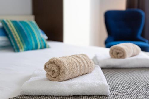 two towels on a bed with a blue chair at Malinska -Krk in Malinska