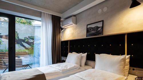 a bedroom with two beds and a large window at Tbilisi Story Hotel in Tbilisi City