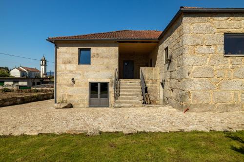 a stone house with a staircase leading to a door at Casa da Veiga in Monção