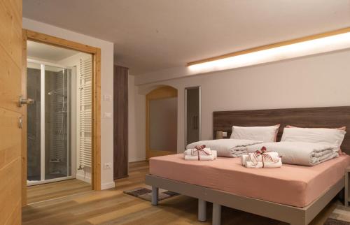 a bedroom with a large bed with two pink shoes on it at L' aurora in Pieve Tesino