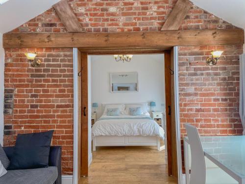 a bedroom with a bed in a brick wall at The Old Dairy in Hickling