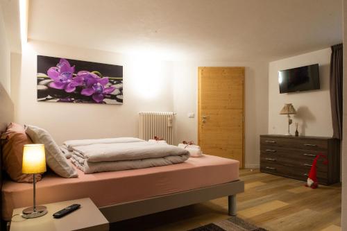 a bedroom with a bed and a dresser with purple flowers on the wall at L' aurora in Pieve Tesino