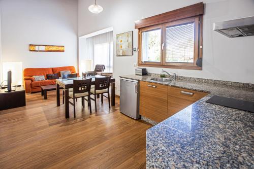 a kitchen and living room with a table and chairs at LA CASONA Encanto Rural - ApartaHotel SPA Llanes in Llanes