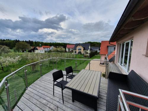 a wooden deck with a table and chairs on a balcony at Pension am Kirschgarten in Gößweinstein