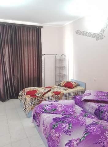 a bedroom with two beds and purple sheets at Old House Hotel in Ureki