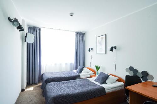 a hotel room with two beds and a desk at Lofft Hotel in Ciechanów