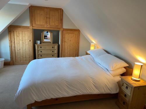 a bedroom with a white bed and wooden cabinets at Islas Cottage, a home in the Heart of Speyside in Dufftown