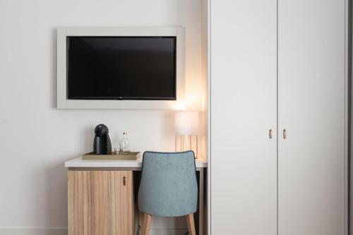 a desk with a chair and a tv on a wall at Zurin Charm Hotel in Lisbon