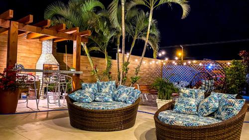 a patio with two chairs and palm trees at night at Hotel & Pousada Favareto in Florianópolis