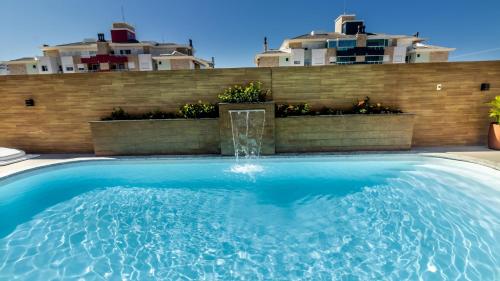 a swimming pool with a fountain in front of a house at Hotel & Pousada Favareto in Florianópolis