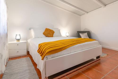 a white bedroom with a bed with a yellow blanket at Apartment Annie 2 in Arco da Calheta
