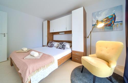 a bedroom with a bed and a yellow chair at Malinska -Krk in Malinska