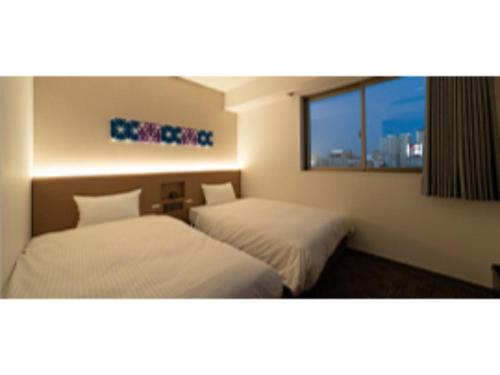 two beds in a hotel room with a window at R&B Hotel Nagoya Ekimae - Vacation STAY 38775v in Nagoya
