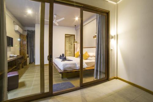 a bedroom with a bed and a large glass window at By the shade Maldives in Hangnaameedhoo