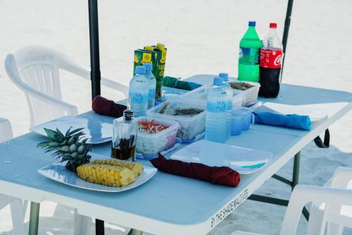 a table with a plate of corn and bottles of water at By the shade Maldives in Hangnaameedhoo