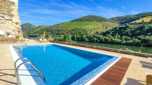 a swimming pool with a view of a river and mountains at Hotel Casa do Tua in Foz Tua