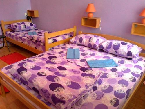 - une chambre avec 2 lits dotés de draps et d'oreillers violets dans l'établissement Hostel M, à Belgrade