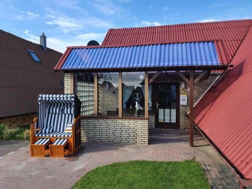 two benches sitting outside of a building with a red roof at Ferienhäuser Seemannsgarn in Friedrichskoog-Spitz