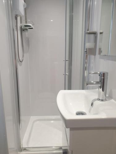 a white bathroom with a sink and a shower at Langroyd Hotel in Blackpool