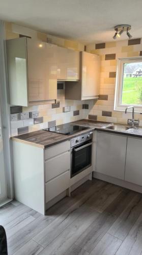 a kitchen with white cabinets and a sink and a window at Chalet at Penstowe Holiday Park Near Bude in Bude