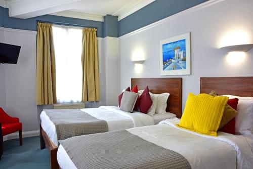 um quarto de hotel com duas camas e uma cadeira vermelha em Royal Oxford Hotel em Oxford