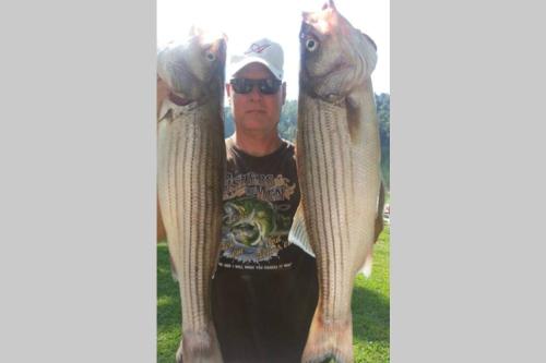 a man holding two fish on his arms at Lakehouse has Spectacular View plus Easy Access! in Rogers