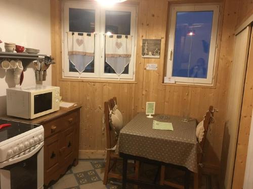 - une cuisine avec une table et un four micro-ondes dans l'établissement Les mélèzes, à Le Mont-Dore