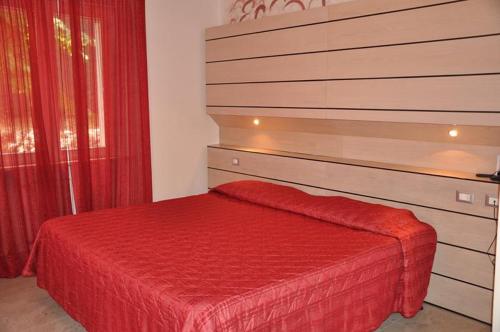 a bedroom with a bed with a red bedspread at Hotel Bristol in Tirrenia