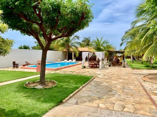 a courtyard with a tree and a swimming pool at Pousada Carmela in Icapuí