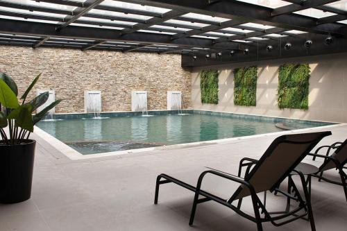 a swimming pool in a building with two chairs at Bella Gramado in Gramado