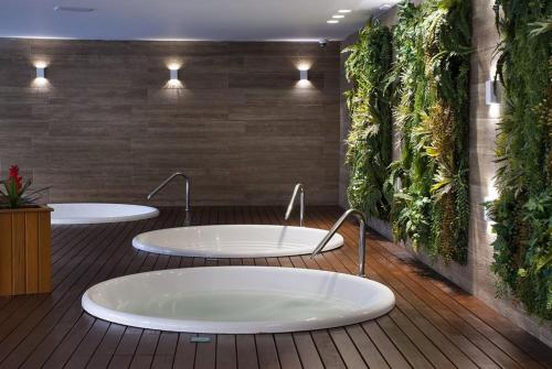 two sinks in a bathroom with plants on the wall at Bella Gramado in Gramado