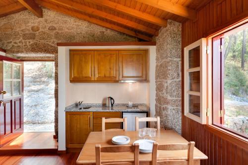 a kitchen with a wooden table and chairs in a room at Quinta do Bárrio - Manor Guest House in Terras de Bouro