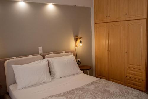 a bedroom with a bed with white pillows and a cabinet at Langi Apartments in Mesolongion