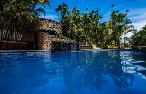 a swimming pool with a waterfall in a resort at Hotel Cibeles Resort in Heredia