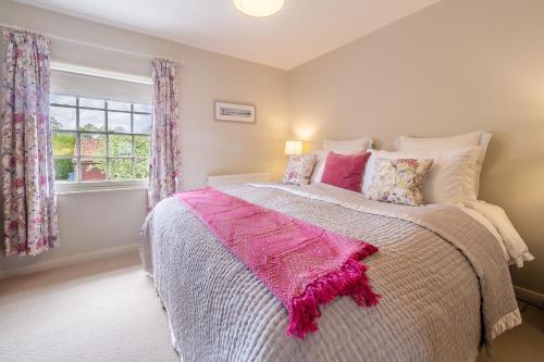 a bedroom with a bed with a pink blanket on it at Immaculate luxury retreat in pretty village with great pubs - Box Valley Cottage in Stoke-by-Nayland