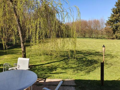 a table and chair in a yard with a tree at Maison Chalet in Grandfontaine