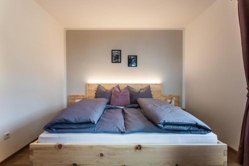 a bed with blue pillows on it in a room at Haidgerberhof - apartments & homemade food in Longostagno