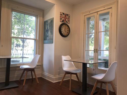 una sala da pranzo con tavolo, sedie e orologio di Harrogate House Inn a Niagara on the Lake