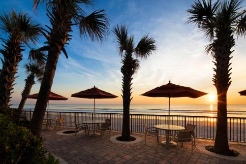 a patio with tables and umbrellas on the beach at Nautilus Inn - Daytona Beach in Daytona Beach