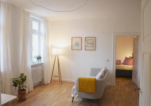 Sala de estar blanca con silla y cama en Die Gründerzeitvilla zwischen Weinstrasse und Pfälzer Wald, en Bad Bergzabern
