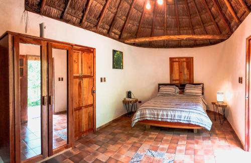 a bedroom with a bed and a wooden ceiling at Hacienda Cenote San Ignacio in Chocholá