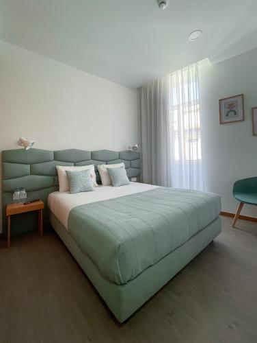 a bedroom with a large bed with a green headboard at Soldouro Train Suites in Aveiro