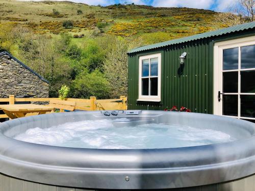 a large hot tub in front of a green building at Mid Wales Luxury Huts in Darowen