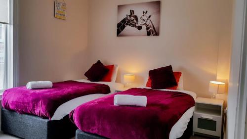 - 2 lits dans une chambre avec des couvertures roses dans l'établissement BellaLiving 2 Bedroom Apartment - Luton, à Luton