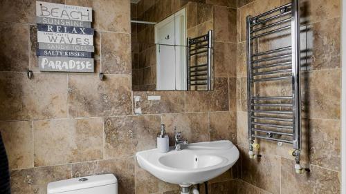 La salle de bains est pourvue d'un lavabo, de toilettes et d'un miroir. dans l'établissement BellaLiving 2 Bedroom Apartment - Luton, à Luton