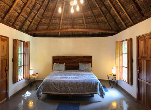 a bedroom with a bed and a wooden ceiling at Hacienda Cenote San Ignacio in Chocholá
