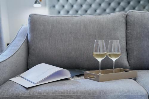 two glasses of white wine and a book on a couch at MiraMe Athens Boutique Hotel in Athens