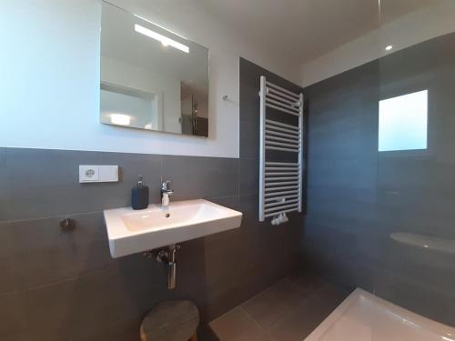 ein Badezimmer mit einem weißen Waschbecken und einem Spiegel in der Unterkunft Gästehaus Maria in Rettenbach am Auerberg